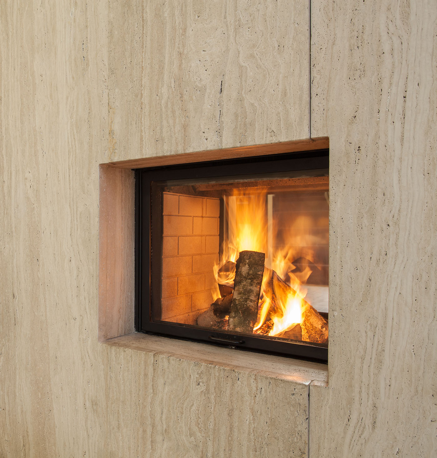Travertine house: Burning fireplace and pieces of wood